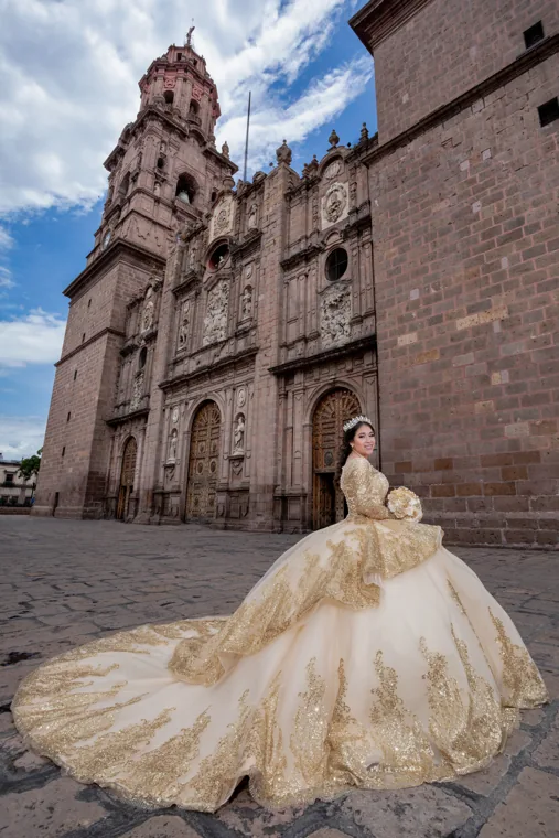 Quinceañera con vestido dorado frente a arquitectura de cantera