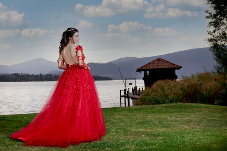 Quinceañera de vestido rojo junto al lago