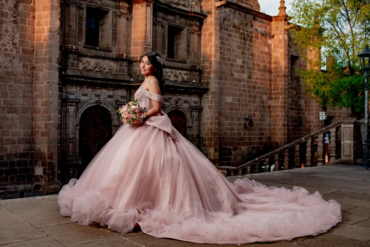 Retrato de quinceañera con vestido rosa en escalinata