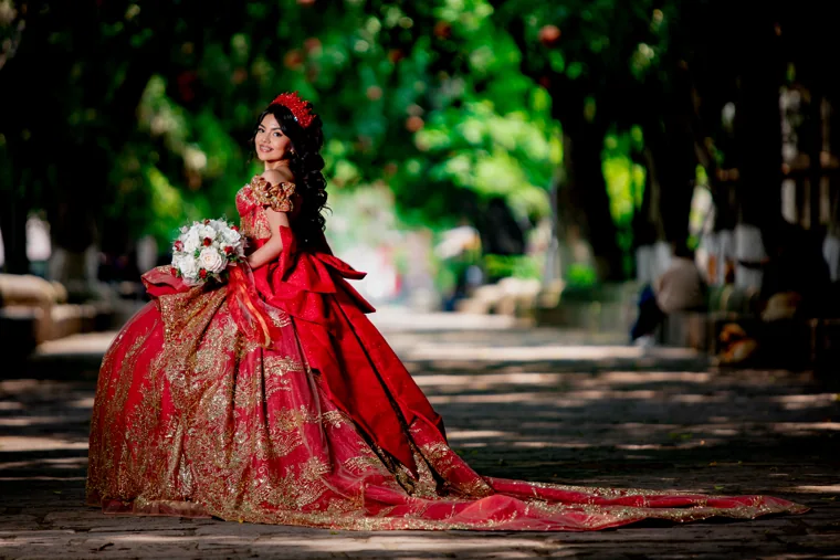 Quinceañera con vestido rojo entre árboles