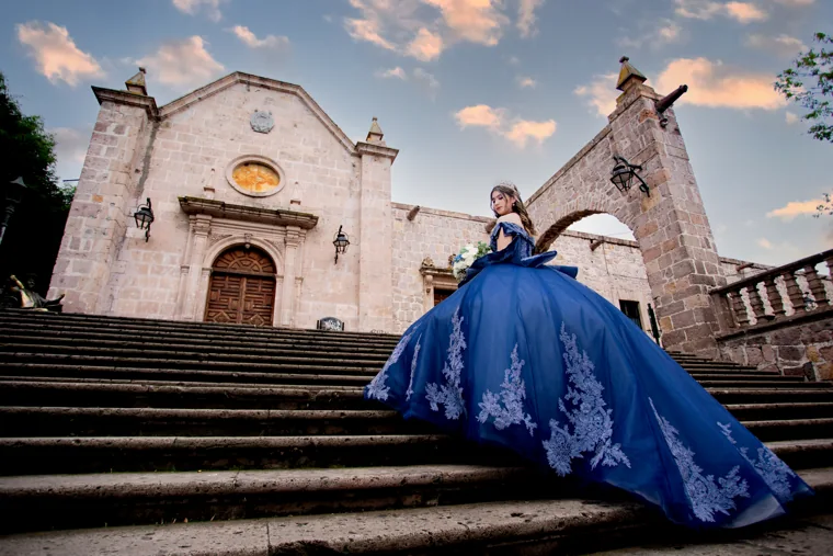 Quinceañera con vestido azul en una escalinata