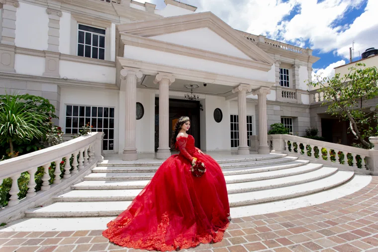 Quinceañera frente a una fachada blanca