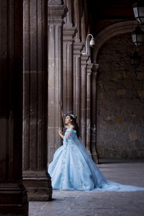 Quinceañera con vestido azul entre columnas